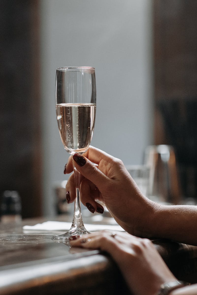 A close-up of a hand holding a champagne flute in a sophisticated setting.