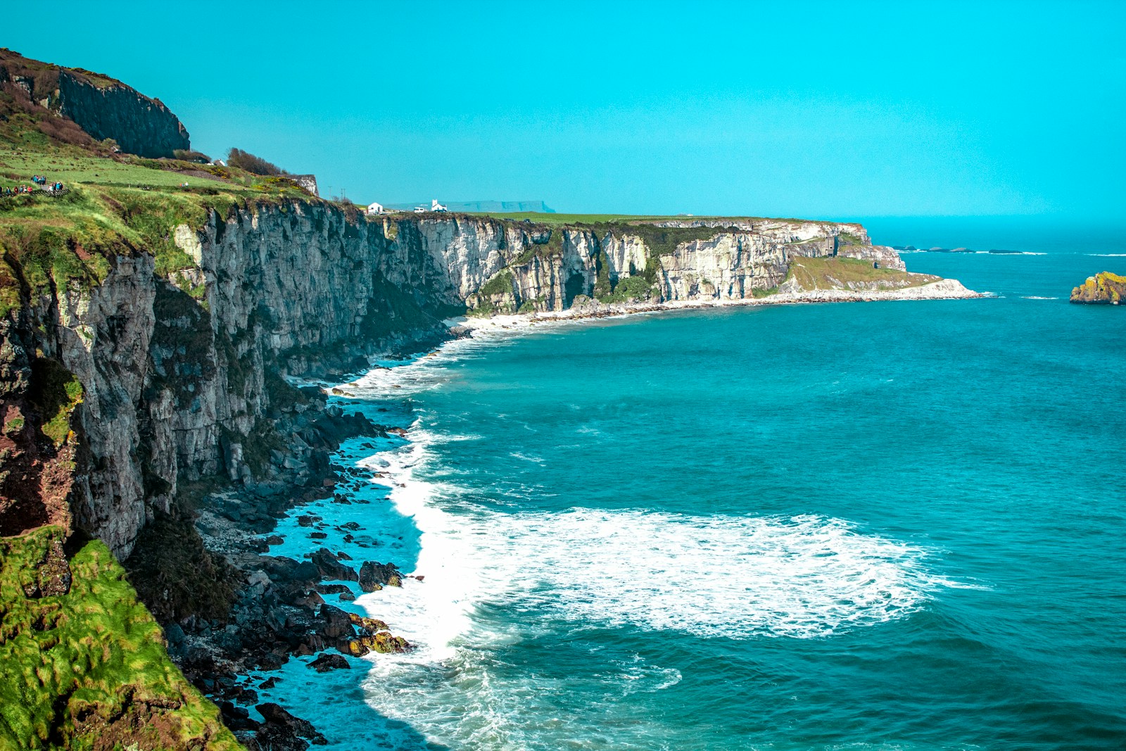 white rock cliff beside body of water'